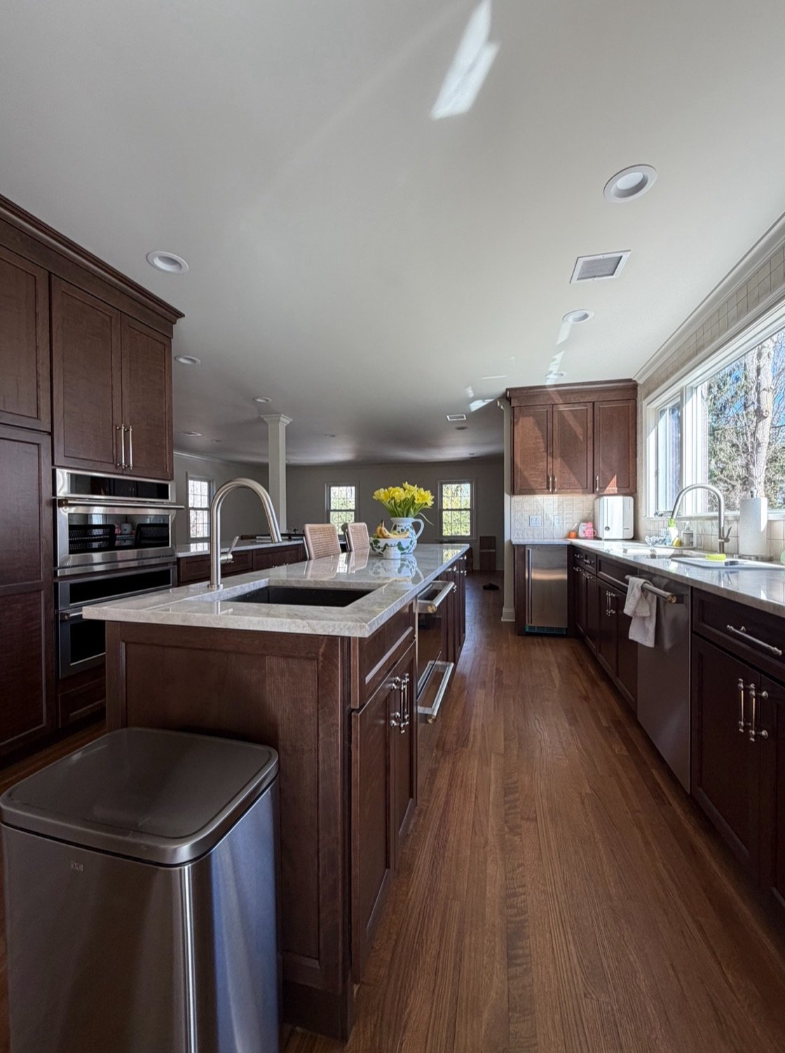 After — remodeled kitchen with dark wood cabinetry, a stone-topped island, and stainless appliances